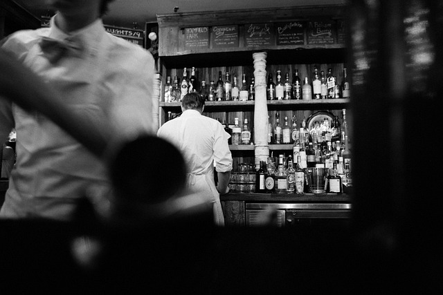 A bartender chilling a bottle of Prosecco in an ice bucket.