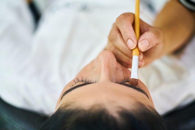 Close-up of a person's hand holding a pen, hovering over a thesaurus page, symbolizing careful word choice.