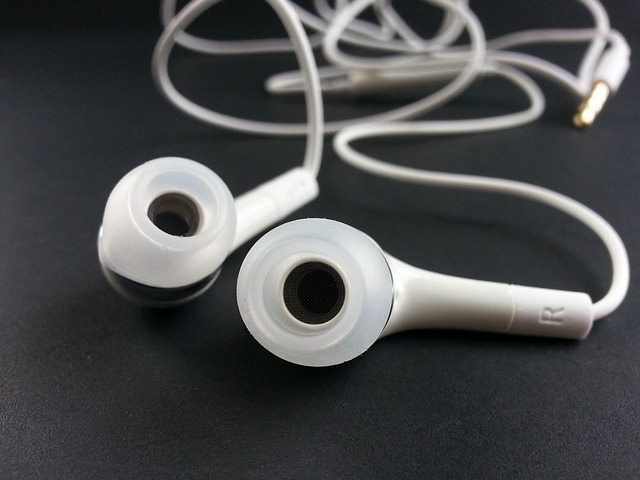Person listening to a technology podcast on headphones with a laptop in the background